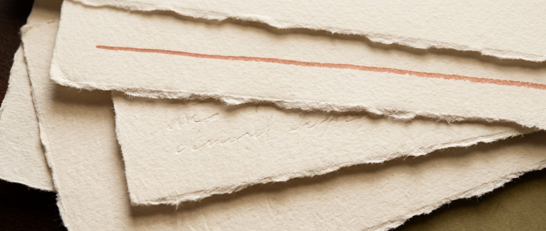 Torn deckled paper marked with a single terracotta line.